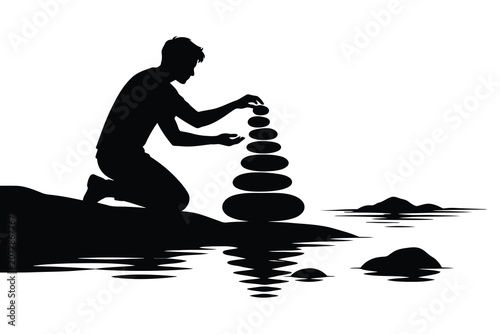 Canvas Print Man kneeling to stack balance stones on a calm lake shore at sunset time