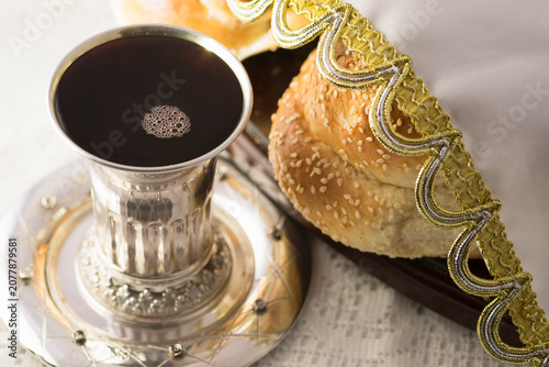 Fotografie A silver Kiddush cup filled with wine alongside a Shabbat Challa (bread)