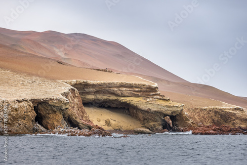 Rugged coastal cliffs and sea caves of the Ballestas Islands rising above the Pacific waters near Paracas