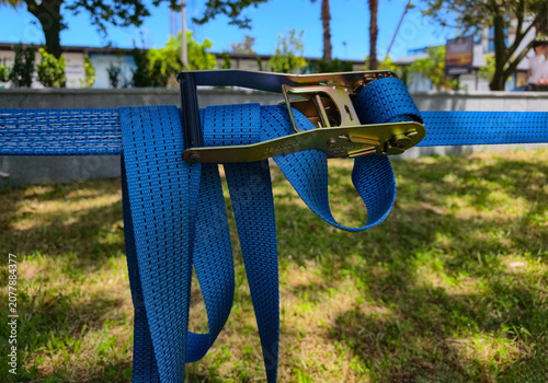 Foto Slackline webbing with ratchet tensioner wrapped around a tree.