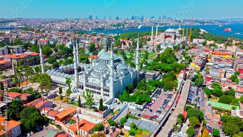 Aerial view of the Blue Mosque in Istanbul, Turkey. The Sultan Ahmed Mosque stands with its domes and minarets near Hagia Sophia, green parks, the Bosphorus and the modern city skyline.