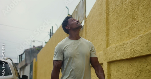 Canvastavla Hispanic Afro-Latin man walking forward along yellow wall, confident and relaxed