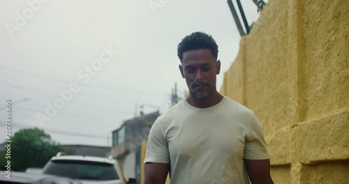 Photos Hispanic Afro-Latin man walking forward along yellow wall, confident and relaxed