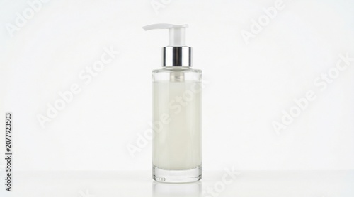 Clear glass bottle with a white pump dispenser containing lotion isolated on white background