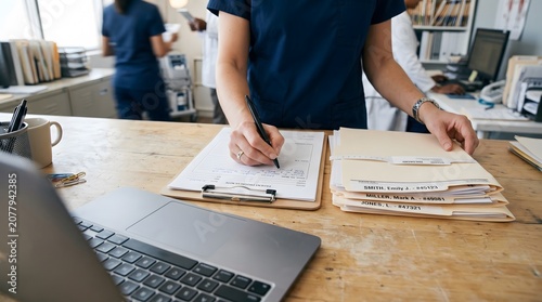 Doctor reviewing patient charts and medical records with laptop on desk