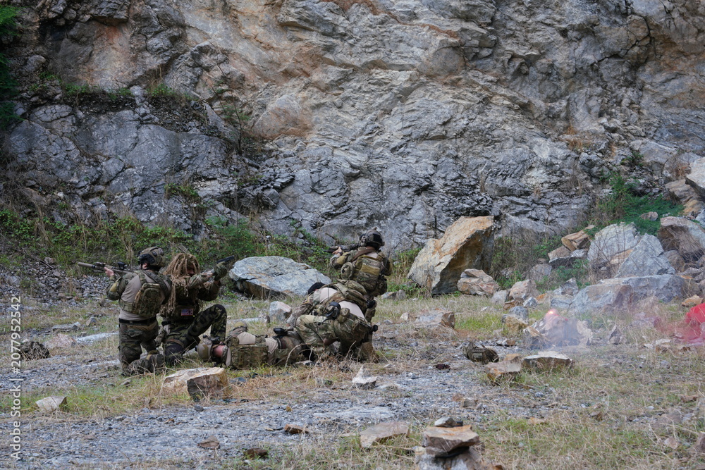 Fototapeta premium A group of soldiers in military uniforms carrying BB guns were randomly attacked and taken down during a military exercise while playing a game. 