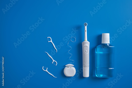 Konstfotografi Top view of set a electric toothbrushes and manual toothbrushes, dental floss and mouthwash on blue background