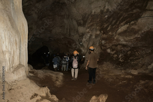 an interior view showcasing the immense scale and raw adventure of exploring the vast, dark limestone cavern of khao wang thong cave in thailand