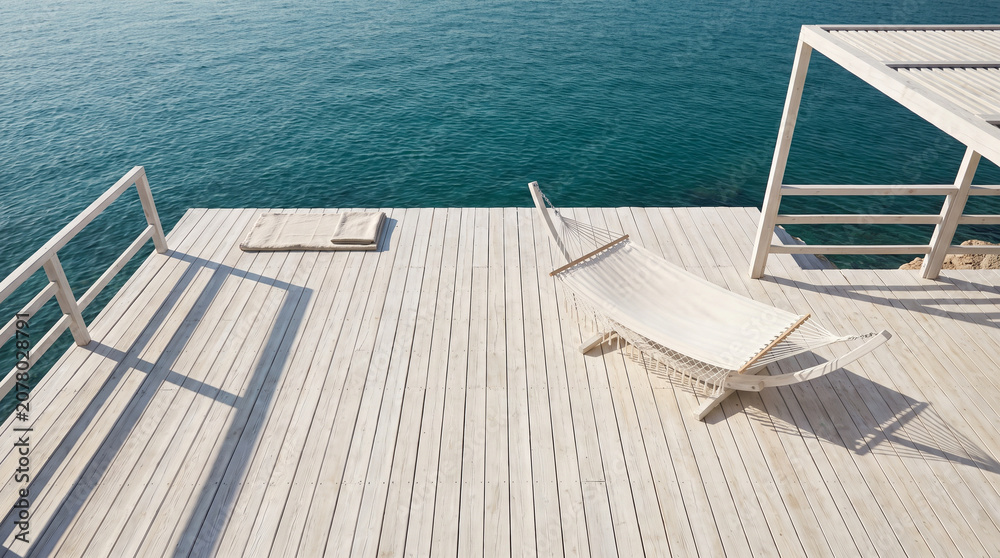Fototapeta premium Top-down view of a white hammock on a wooden deck by turquoise sea providing copy space for luxury travel advertising.