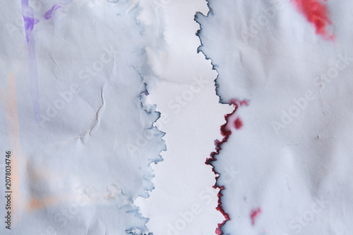 White paper stained with blue and red ink on left and right side with narrow empty space in the middle