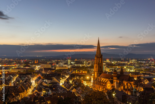 Evening view of Freiburg with illuminated cathedral and city lights