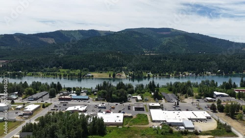 Aerial of Priest River small mountain town with riverfront community and mountain backdrop in summer