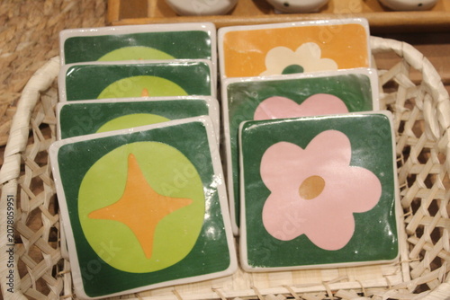 Square ceramic coasters decorated with colorful floral and geometric painted shapes.