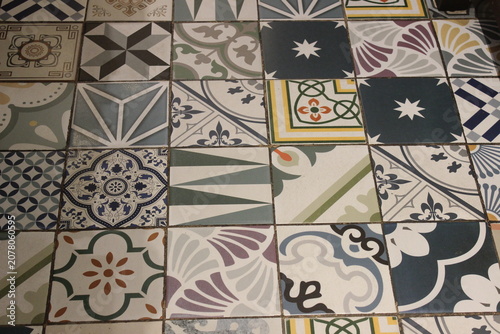 Geometric floor tiles with various patterns installed in outdoor public walkway.