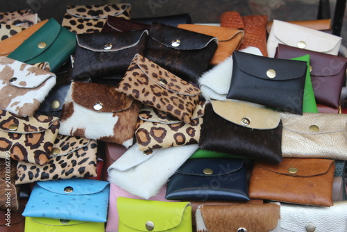 Pile of assorted handmade leather wallets and purses on display at outdoor market.
