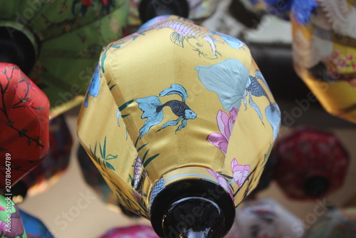 Golden yellow lantern with koi fish and floral painting in a traditional setting.