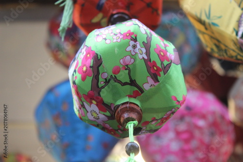 Green fabric lantern with cherry blossom print displayed at a festive craft fair.