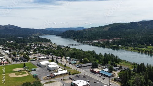 Aerial of small town along Priest River in Bonner County Idaho with a wide river flowing through the forested valley in summer