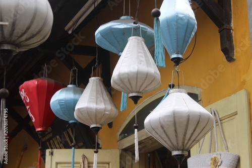 Colorful silk lanterns suspended in row outside craft shop in ancient hoi an town.