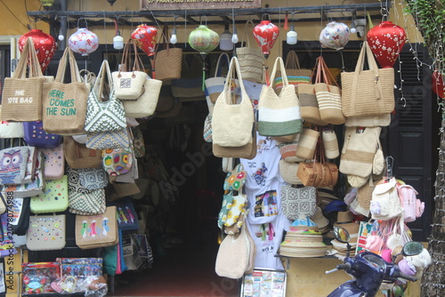Woven straw tote bags and traditional lanterns displayed at shop front in vietnam.