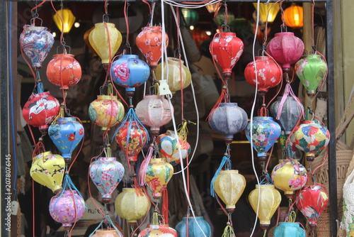 Collection of vibrant silk lanterns hanging in a traditional storefront in Vietnam.