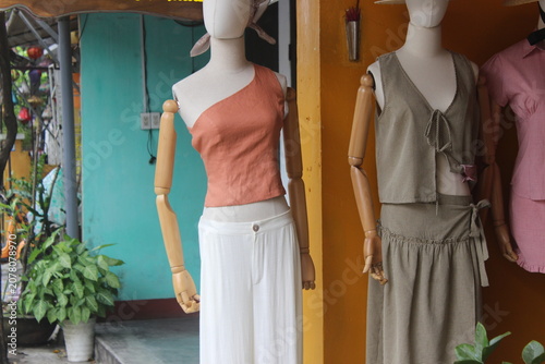 Mannequins showcasing stylish casual summer clothing inside boutique shop window.