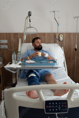 Fotografía A vertical shot of a bearded middle-aged man in a hospital gown sitting in bed w
