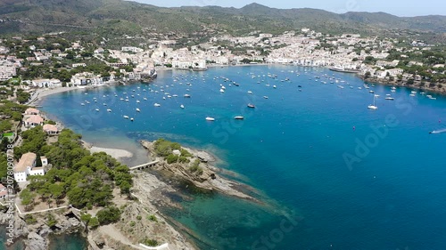Aerial view of the picturesque fishing village of Cadaqués, featuring its whitewashed houses, historic waterfront, peaceful harbor and the crystal-clear waters of the Mediterranean on the Costa Brava.