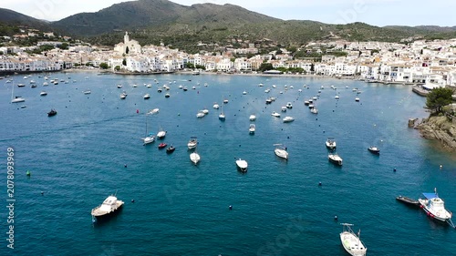Aerial view of the picturesque fishing village of Cadaqués, featuring its whitewashed houses, historic waterfront, peaceful harbor and the crystal-clear waters of the Mediterranean on the Costa Brava.