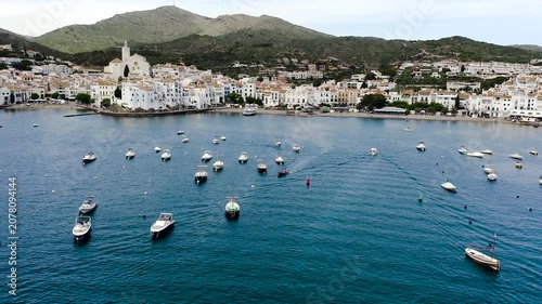 Aerial view of the picturesque fishing village of Cadaqués, featuring its whitewashed houses, historic waterfront, peaceful harbor and the crystal-clear waters of the Mediterranean on the Costa Brava.
