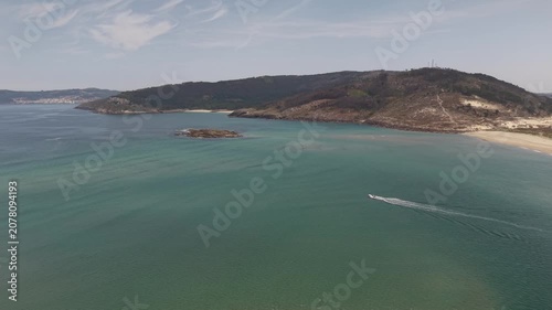 Aerial view showing a speed boat cruising by the sandbank and coastline of galicia
