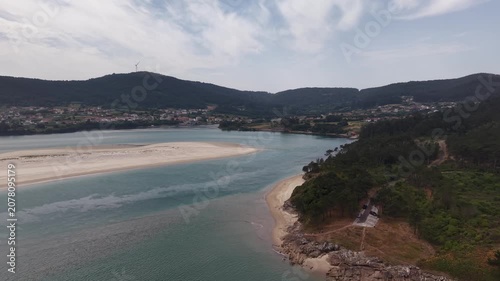 Aerial view showing a speed boat cruising by the sandbank and coastline of galicia