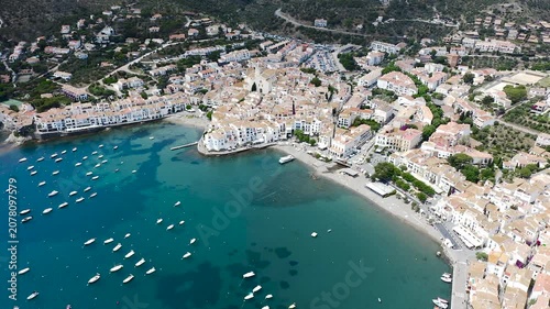 Aerial view of the picturesque fishing village of Cadaqués, featuring its whitewashed houses, historic waterfront, peaceful harbor and the crystal-clear waters of the Mediterranean on the Costa Brava.
