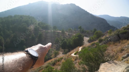 POV, male hand pointing the landscape on background.