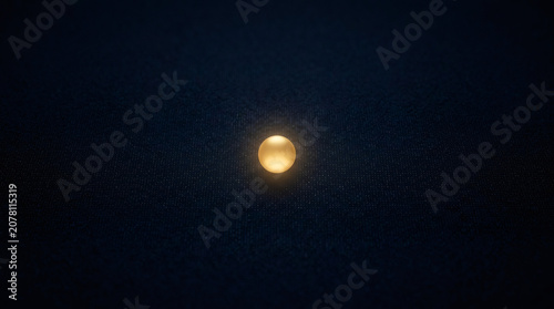 Glowing golden sphere centered on a deep dark textured background. Minimalist abstract composition representing unity and focus. Symbolic light source in shadows for modern design project.