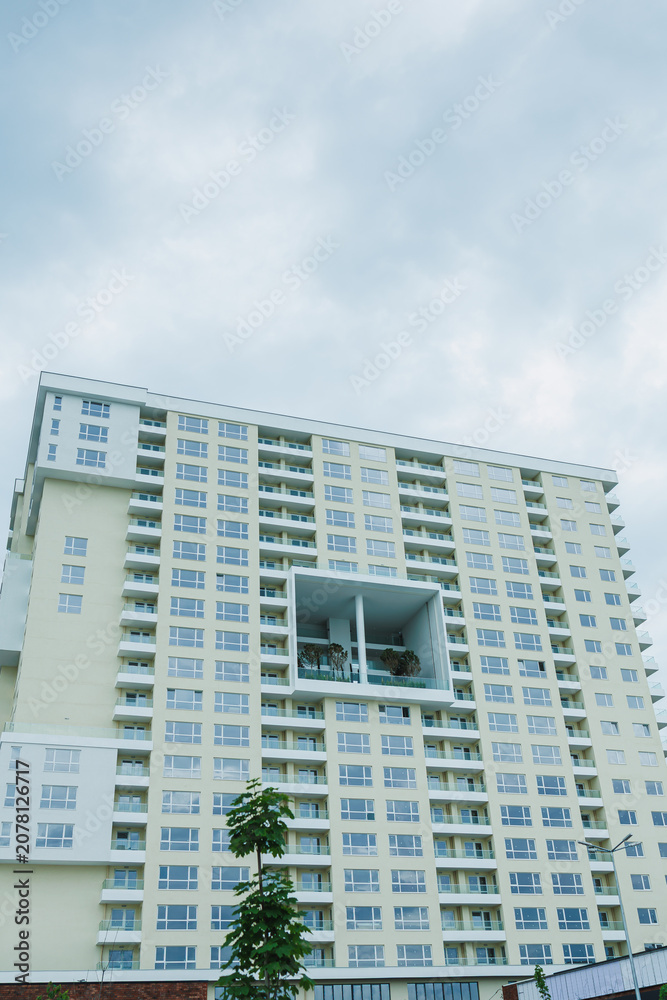 Fototapeta premium Building stands tall with many windows showing modern design in an urban area during cloudy weather