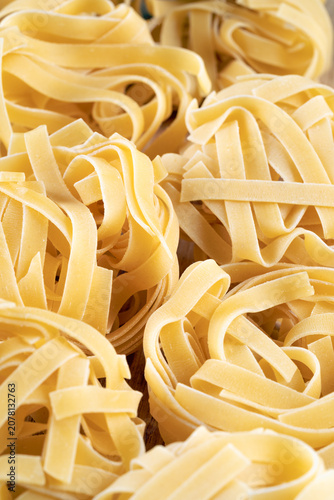 Full frame macro background texture of dry golden Italian fettuccine nests, ideal for food concepts