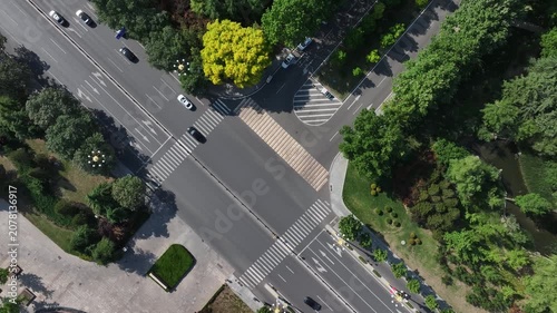 Aerial view of a city road intersection surrounded by lush green trees and traffic flow