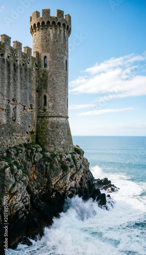 spanish castle's imposing stone walls and a round tower on a cliff edge