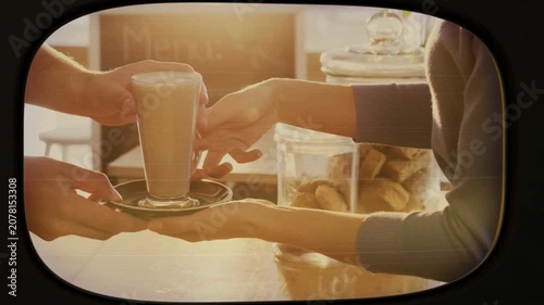 Left hand extending saucer, right hands sliding under saucer, steadying latte transfer for customer