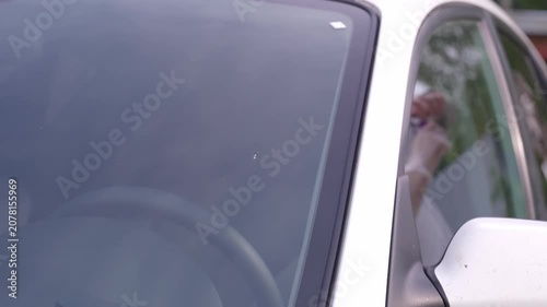 A man applies a ceramic anti-rain coating to the windows and headlights of a car.