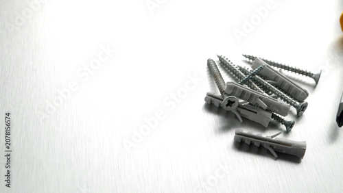Assorted screws and plastic wall plugs on a brushed metal background