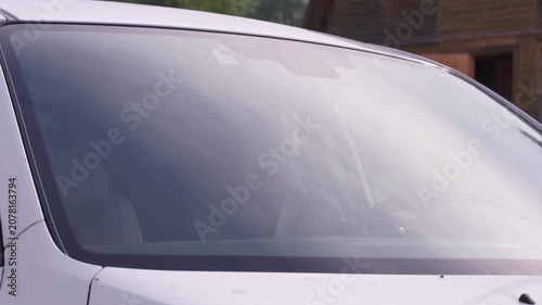 A man applies a ceramic anti-rain coating to the windows and headlights of a car.