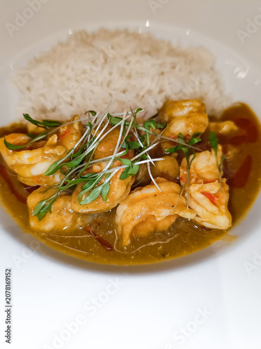 Selective focus in shrimp curry dish with microgreen vegetables and blurred white rice