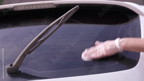 A man applies a ceramic anti-rain coating to the windows and headlights of a car.