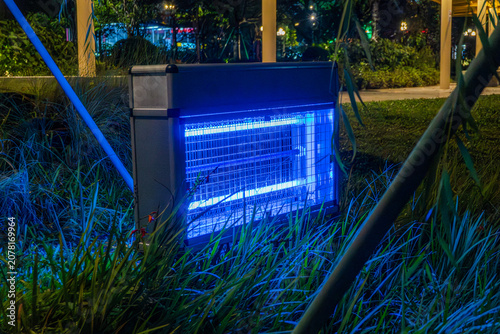 Obraz na plátně Outdoor bug zapper glowing at night in garden setting with blue light for insect