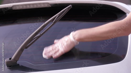 A man applies a ceramic anti-rain coating to the windows and headlights of a car.