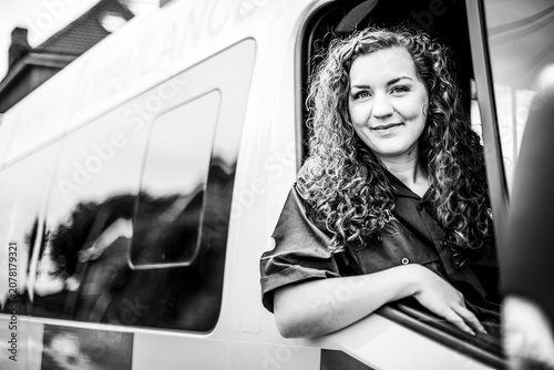 Εκτύπωση καμβά Curly-haired woman smiling from van doorway in black and white
