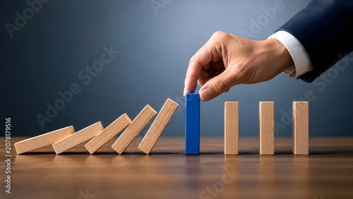 Corporate risk mitigation strategy showing a hand placing a blue barrier to stop a falling domino chain reaction