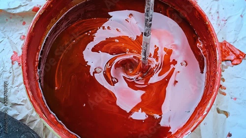 Mixing a red paint in a construction site for paint renovation with a drill. Nice color effect.  